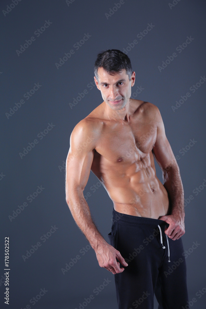 Fototapeta premium muscular man. Muscular man on a grey background showing muscles. Fitness instructor. Fitness professional. Workout. Men's fitness.