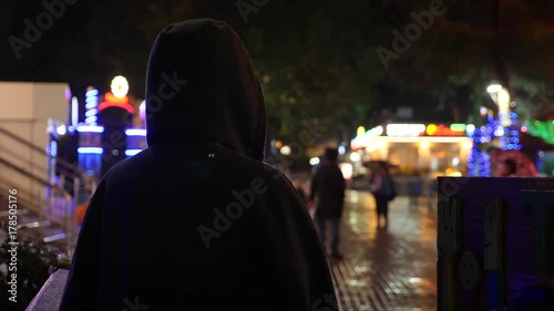 Silhouette of a man in a hood standing on a night street. 4k