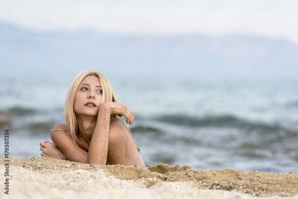 Slim gorgeous blonde woman lying topless on sand, photo in horizontal Slim gorgeous blonde woman lying topless on sand, photo in horizontal