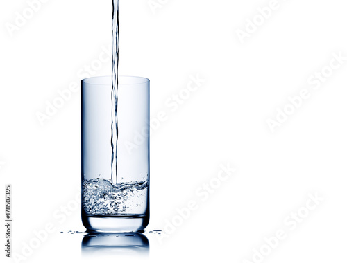 Water pouring and splashing into glass isolated on white with reflection