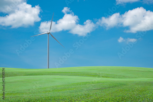 Green grass field with wind turbine for alternative energy blue sky and cloud background,copy space for your text and design background.