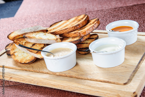 Slice of toast roasted in breaded with cheese and sesame slipped in a sauce on a wooden board photo