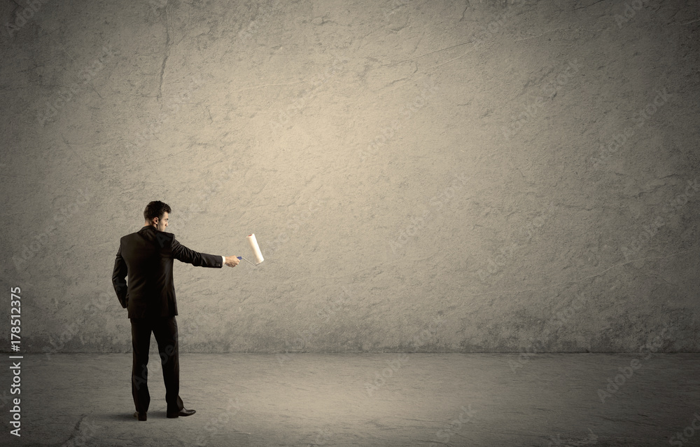 Salesman with roller standing at empty wall Salesman with roller standing at empty wall