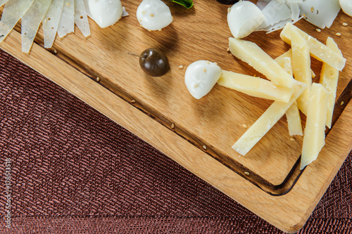 Assortment of cheese on a rustic cutting board wooden background..