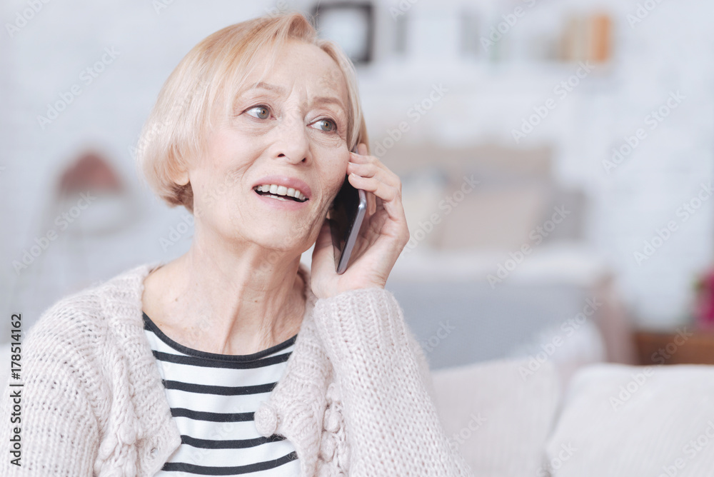 Excited retired woman having smartphone call indoors Excited retired woman having smartphone call indoors