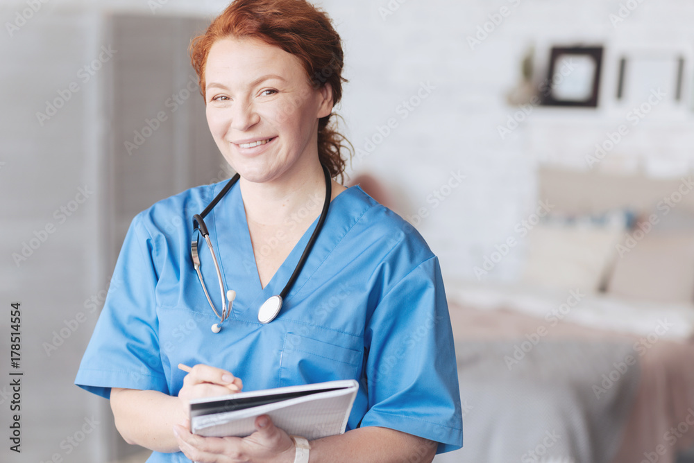 © zinkevych - Friendly looking nurse with notebook smiling into camera