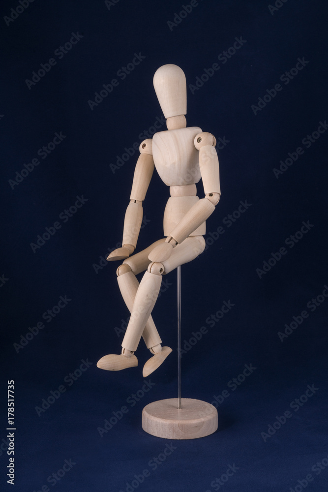 a wooden dummy in sitting position with a blue background a wooden dummy in sitting position with a blue background