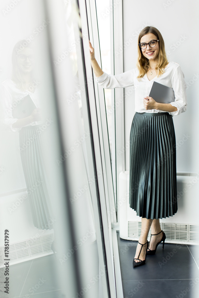 Young businesswoman standing wirth tablet in the office by window Young businesswoman standing wirth tablet in the office by window