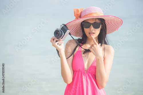 Portrait of Beautiful Asian Woman holding retro Camera at the Beach, People with Summer Concept,  Woman with Happy Emotion on Vocation.