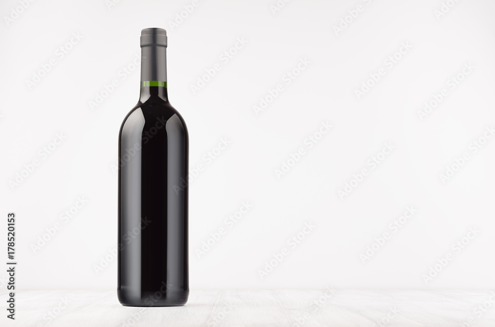 Black wine bottle with red wine on white wooden board, mock up. Template for advertising, design, branding identity. Black wine bottle with red wine on white wooden board, mock up. Template for advertising, design, branding identity.