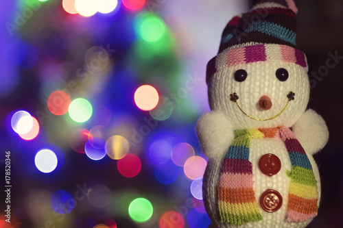 Toy snowman and Christmas lights in the background