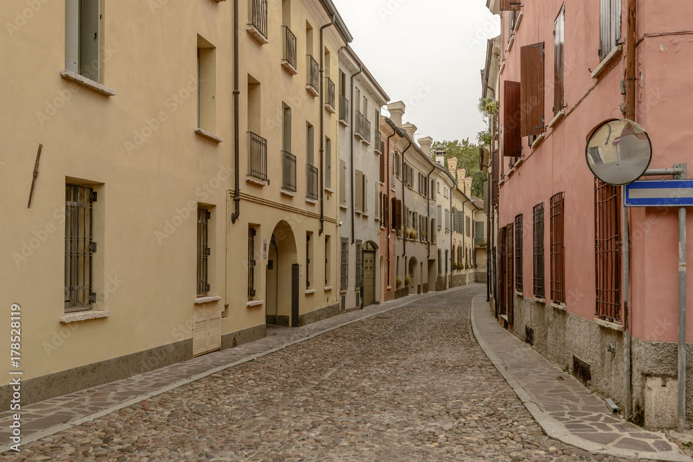 old houses on bending cobbled street in city center, Mantua, Italy