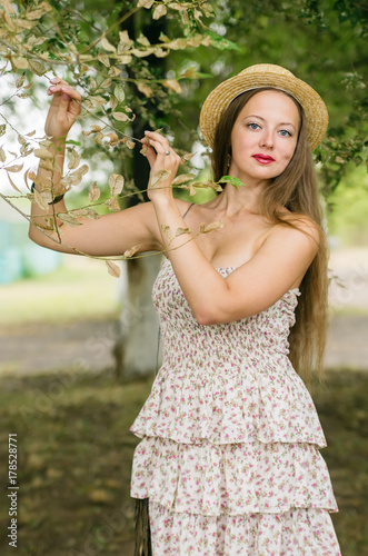 Girl in a straw hat and summer dress posing in a city park / Photographed in Russia, Orenburg
