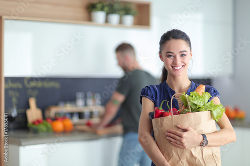 Young couple in the kitchen , woman with a bag of groceries shopping photo