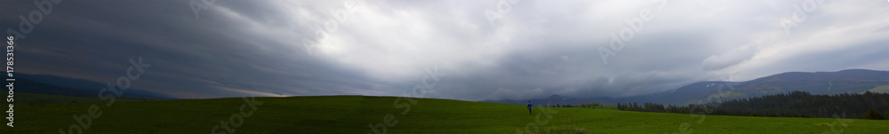 Panorama in the mountains in cloudy weather, a lonely man turned his back Panorama in the mountains in cloudy weather, a lonely man turned his back