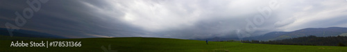 Panorama in the mountains in cloudy weather, a lonely man turned his back