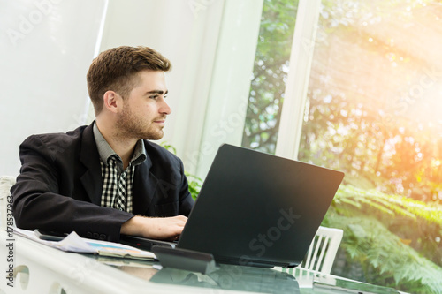 businessman in suit working with laptop morning time with backgrround of green garden
