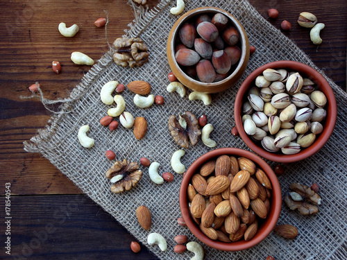 different varieties of nuts on a wooden background - almonds, cashews, walnuts, hazelnuts, pistachios