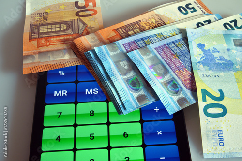 risparmiare, guadagnare e investire denaro  un mucchietto di banconote in valuta euro e accanto una calcolatrice. close-up © lucio pepi