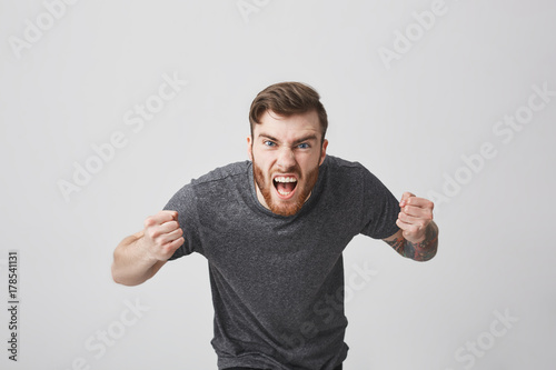 Body language. Beautiful strong bearded caucasian man with tattoo on arm expressive gesticulating with hands, screaming loudly on stadium, cheering his favourite rugby team in final game photo