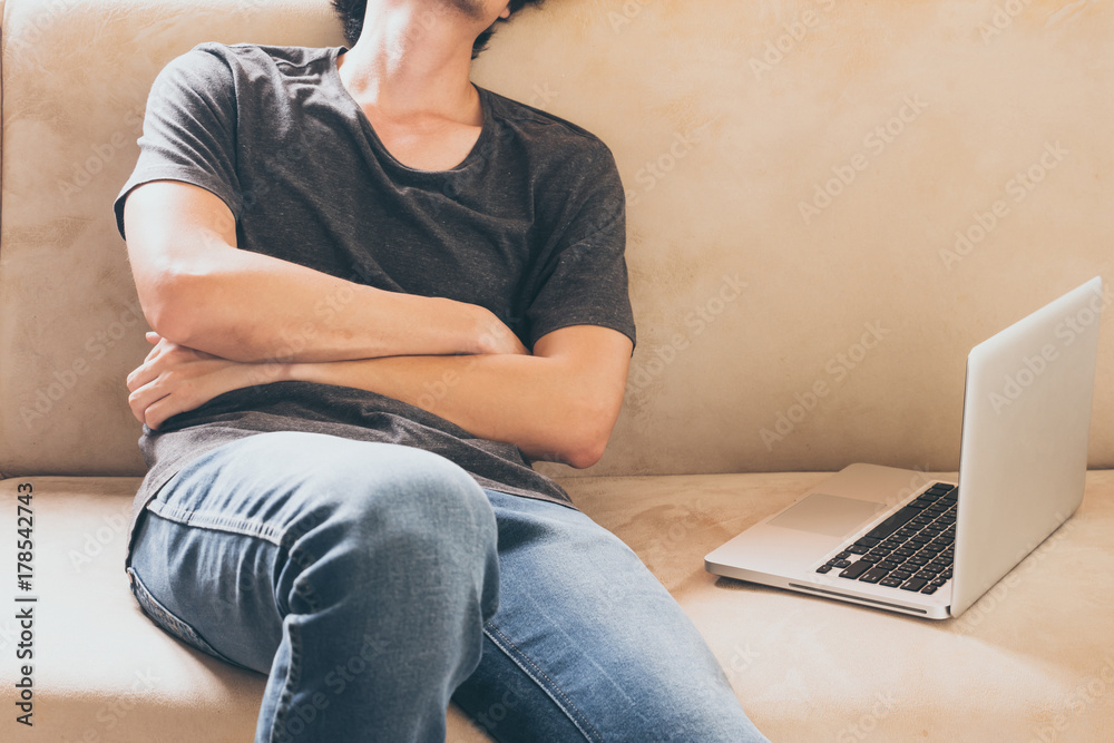 Naklejka premium Close up of young man sleeping on the sofa at home with laptop.