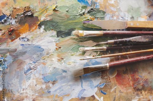 Dirty paint brushes. Artists brushes and oil paints on wooden palette.