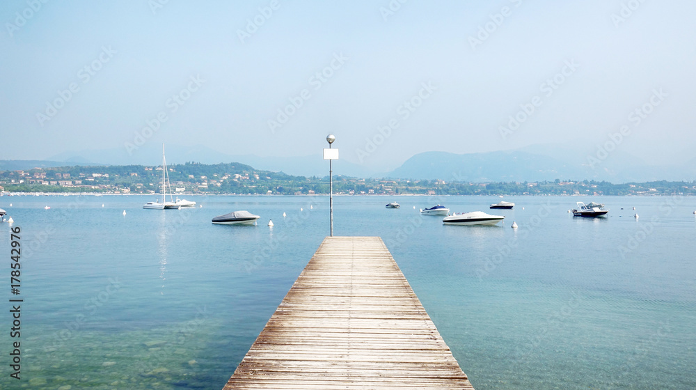 Obraz premium Wooden Pier in the middle of the Beautiful Garda Lake Scenery, Italy.