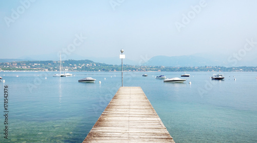 Wooden Pier in the middle of the Beautiful Garda Lake Scenery, Italy.