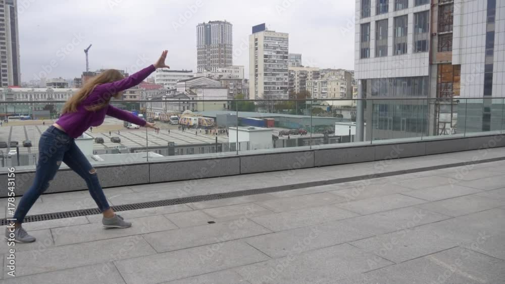 Young attractive woman doing acrobatics with cityscape on background. Young attractive woman doing acrobatics with cityscape on background.