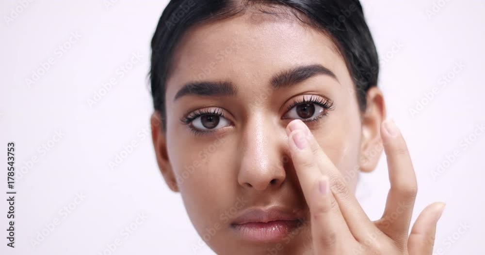 Applying eye cream in small dots under eyes and gently massaging it in isolated on white Applying eye cream in small dots under eyes and gently massaging it in isolated on white