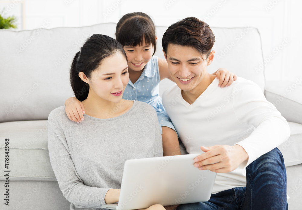 Fototapeta premium Happy asian family with laptop on sofa