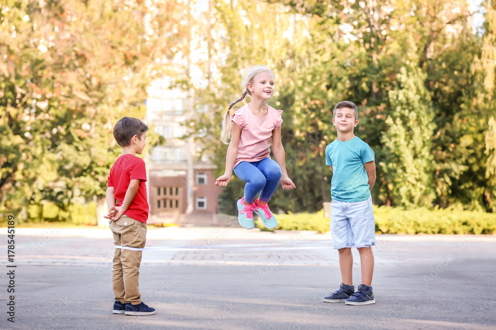 Adorable children playing elastic game outdoors Adorable children playing elastic game outdoors