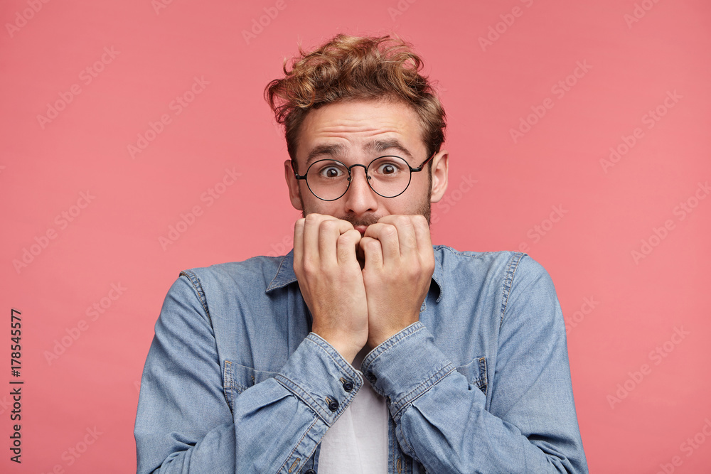Nervous embarassed man bites nails, looks worried before visiting doctor or dentist. Anxious concerned male student feels anxiety before passing course or diploma paper, afraid of difficult questions Nervous embarassed man bites nails, looks worried before visiting doctor or dentist. Anxious concerned male student feels anxiety before passing course or diploma paper, afraid of difficult questions