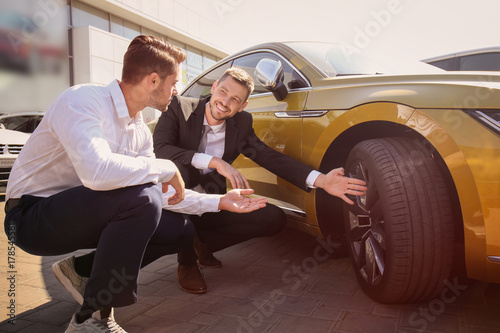 Salesman showing new car to...