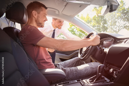 Salesman showing new car to...