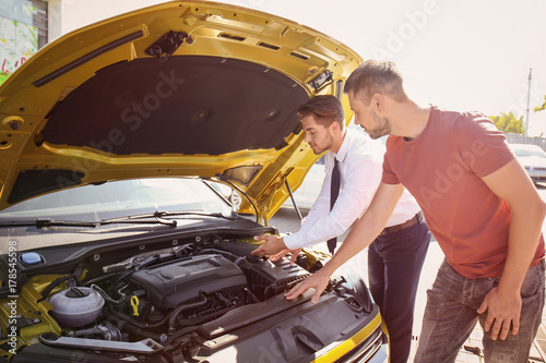 Salesman showing new car to...