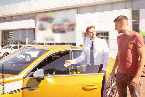 Salesman showing new car to...