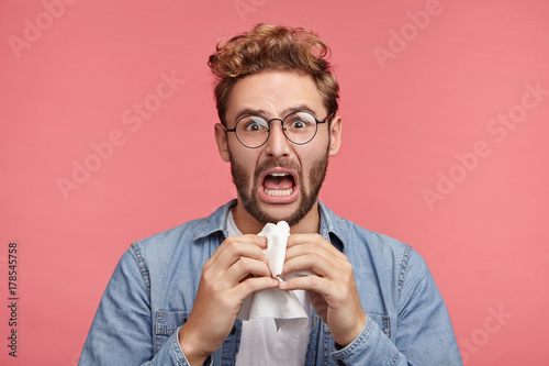 Tela Sorrorful grieved man has misfortune, going to cry, holds handkerchief to wipe tears, has unhappy discontent expression, isolated over pink background
