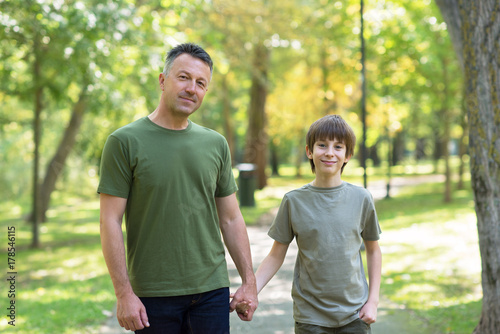 Portrait of father with his son walking together in autumn park. Family leisure. Parenting. Parenthood. © Khorzhevska