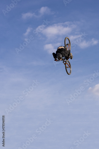 Man on mountain bike jump and fly against blue sky