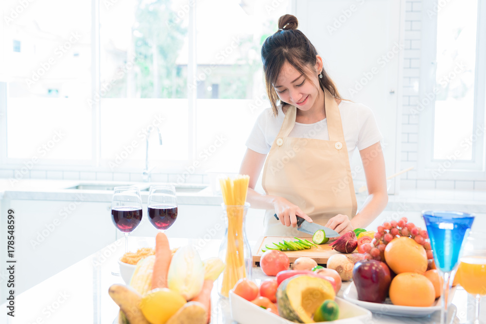 Woman cooking and slicing vegetable in kitchen room with full of food and fruit on table. Holiday and Happiness concept. Woman cooking and slicing vegetable in kitchen room with full of food and fruit on table. Holiday and Happiness concept.