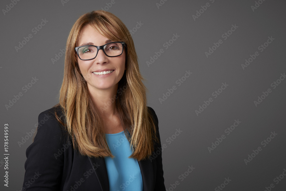 Attractive middle aged businesswoman against grey background.