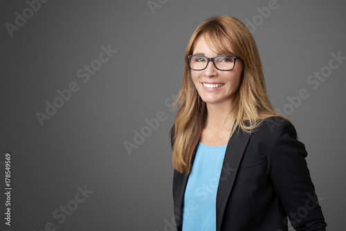 Attractive middle aged businesswoman against grey background.