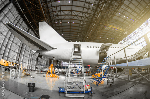 Large passenger aircraft on service in an aviation hangar rear view of the tail, gangway ladder entrance.