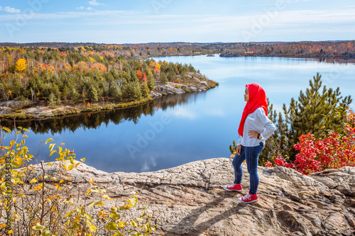 A muslim teenager enjoying view of a lake from top of the hill during fall season