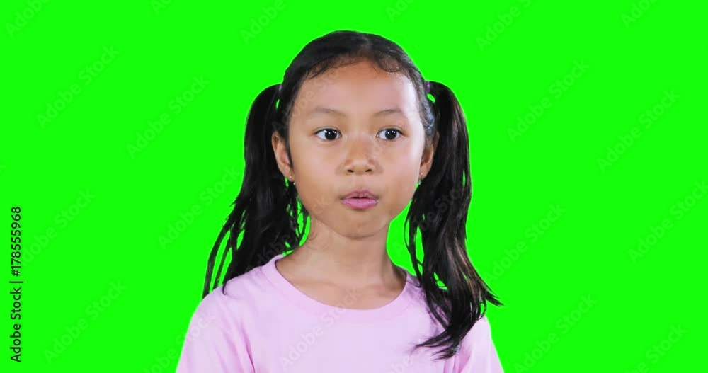 Adorable little girl with pigtail hair, chewing and blowing gum in the studio with green screen background. Shot in 4k resolution Adorable little girl with pigtail hair, chewing and blowing gum in the studio with green screen background. Shot in 4k resolution