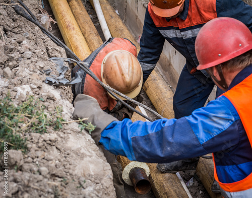 A group of male workers push the heating pipe