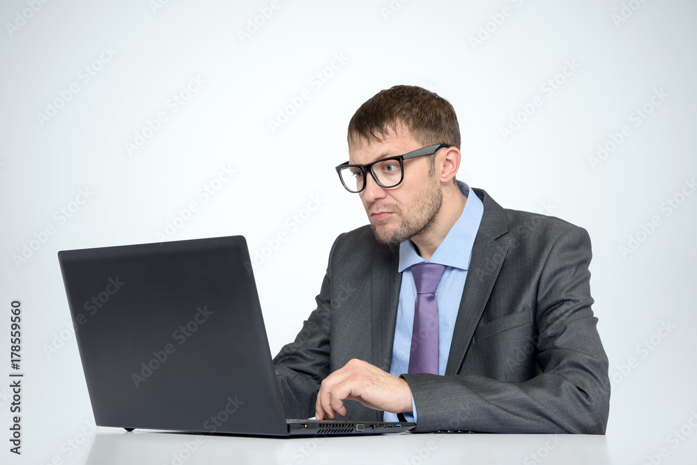 Working bearded man in glasses with a laptop on light background Working bearded man in glasses with a laptop on light background