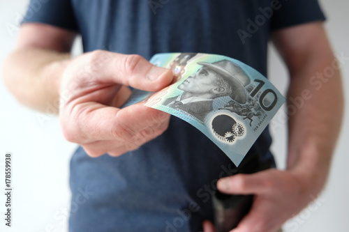 A man holding out a ten dollar Australian currency to buy, donate, share, pay someone, or invest. What can you get for ten dollars today? photo