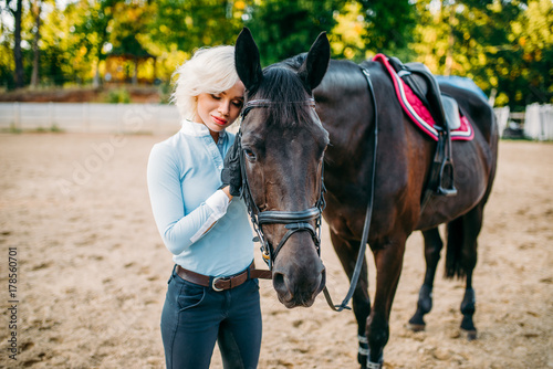 Female rider hugs her horse, horseback riding